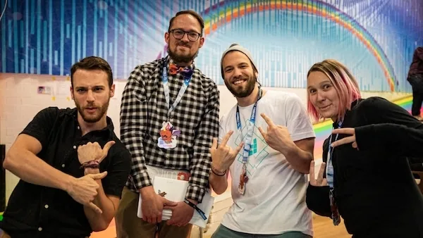 Four ETHDenver attendees posing in front of a rainbow mural