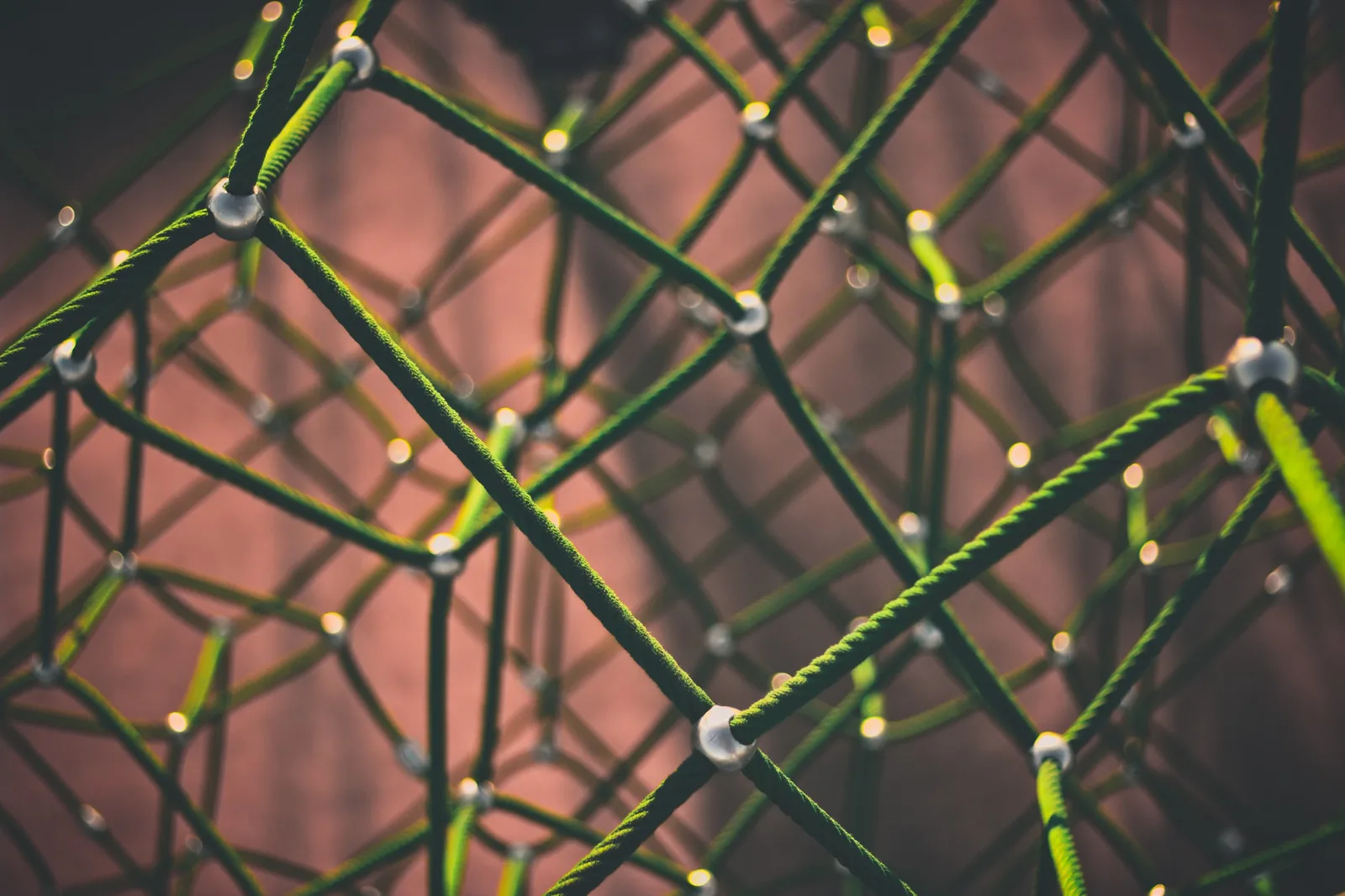 Close-up of green rope netting joined by metal nodes