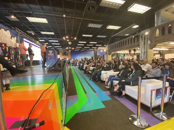 The ETHDenver venue: a crowd watching a stage, on a floor striped with brightly colored tape